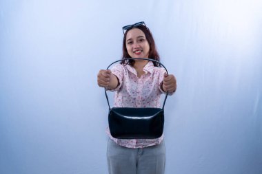 Beyaz çiçekli elbise giyen Endonezyalı kadın gülümsüyor ve siyah çanta gösteriyor.