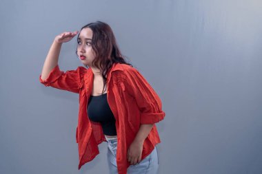 Turuncu elbise giyen Endonezyalı bir kadın çok uzaklarda bir şeye bakıyor..