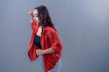 Turuncu elbiseli Asyalı kadın birine vurmak istiyor.