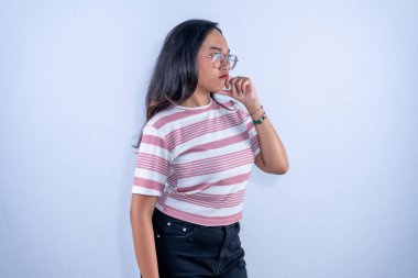 Pembe ve beyaz çizgili gözlüklü Endonezyalı kadın dalgın görünüyor.