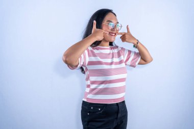 Dişlerini gösteren gözlüklü pembe ve beyaz çizgili tişörtlü Endonezyalı kadın.