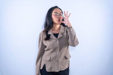 Endonezyalı, kahverengi ceketli, gözlüklü bir kadın güzel bir işaret veriyor.