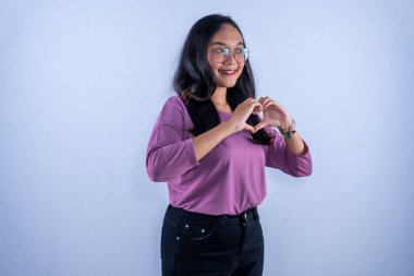 Mor gömlek, gözlük takan, gülümseyen ve aşk işareti yapan Endonezyalı Asyalı kadın.