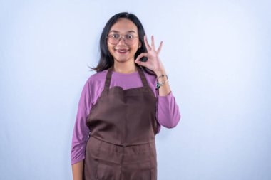 Mor gömlekli, kahverengi önlüklü, gözlüklü, tamam işareti veren Endonezyalı Asyalı kadın