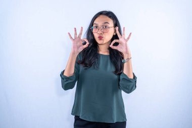 Endonezyalı mavi gömlekli ve gözlüklü kadın iki tamam işareti veriyor.