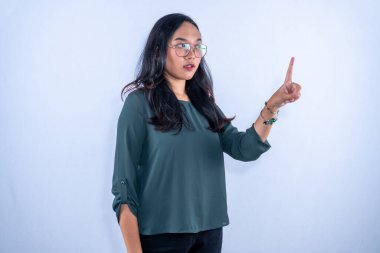 Mavi gömlek ve gözlük takan Endonezyalı bir Asyalı kadın kızgın olduğunu göstermek için işaret parmağını kaldırıyor..