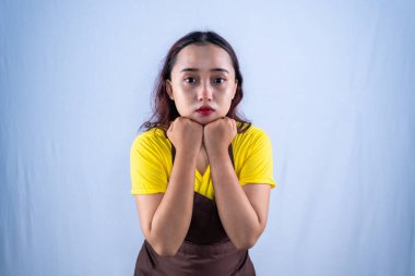 Sarı tişörtlü ve kahverengi önlüklü Asyalı kadın.