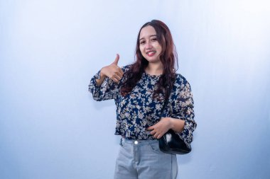 Siyah çiçekli elbiseli Endonezyalı kadın gülümsüyor ve işaret veriyor.