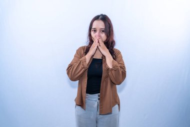 Kahverengi elbiseli Endonezyalı kadın iki eliyle ağzını kapatıyor.