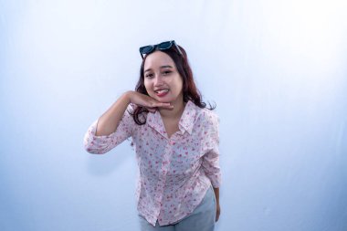 Beyaz desenli elbiseli Endonezyalı kadın gülümseyerek çenesini tutuyor.