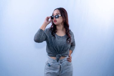 Endonezyalı gri elbiseli, güneş gözlüğü takan ve elinde tutan Asyalı kadın.