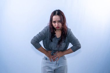 Gri gömlekli Asyalı kadın midesini tutarken acı çekiyor.