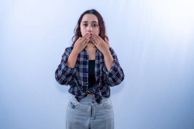 Siyah kareli gömlekli Endonezyalı kadın iki eliyle ağzını kapatıyor.
