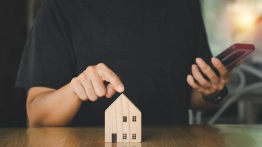 Gayrimenkul yatırım işi konsepti. İşadamı ahşap model evi işaret ediyor. En iyi evi seç ve karar ver..  