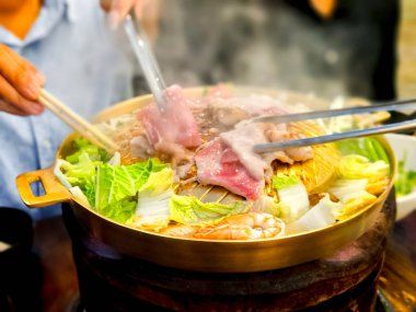 Tayland usulü barbekü. Sıcak tavada ızgara et ve domuz eti sebzeli ve fırında lezzetli bir çorba.