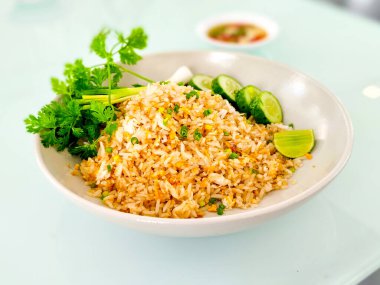 Lezzetli Tayland yemekleri. Dilimlenmiş salatalıklı kızarmış pirinç, yeşil soğan ve beyaz tabakta limon..