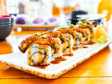 Lezzetli Japon yemeği ve konsepti. Japon restoranında beyaz tabak üzerine teriyaki soslu Unagi suşi maki rulosu..