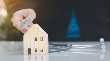 Ev onarımı ve müfettiş konsepti. Steteskop ve ahşap ev modeli. Ev ve emlakları gün ışığıyla kontrol ediyorum..