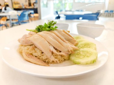 Tavuklu buğulanmış pirinç ve beyaz tabakta salatalık. Lezzetli bir sokak yemeği. Yüksek protein besin değeri.  