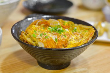Japon yemeği konsepti. Tavuk ve yumurta kasesi mi yoksa yeşil soğanlı siyah bir kasede Oyakodon mu?. 