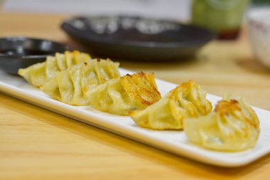 Japon yemeği konsepti. Gyoza, beyaz dikdörtgen bir tabakta soya sosuyla servis edilir.. 