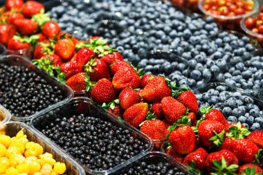 Markette farklı taze meyvelerin renkli karışımı. Ahududu, çilek, yabanmersini ve yabanmersini