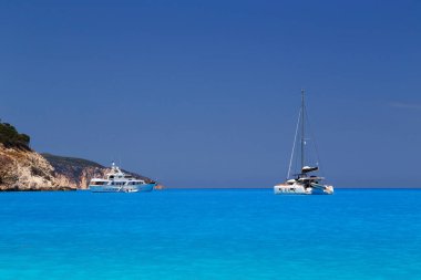 Beyaz yatlar Myrtos Sahili turkuaz ve mavi körfeze demirlemiş. Sefalonya Adası, Yunanistan ve Avrupa 'daki ünlü ve son derece popüler seyahat merkezinin yaz manzarası
