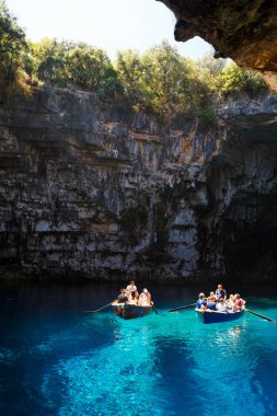 Melissani Mağarası, Cephalonia Adası, Yunanistan - 14 Temmuz 2019: Melissani Gölü 'nün ortasında turistli küçük tekneler ve fantastik mavi deniz suyu