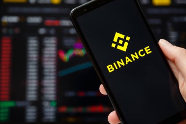 Ukrayna, Odessa - Haziran, 12021: Arka planda ticaret grafiğiyle çalışan Binance mobil uygulaması ile akıllı telefonu kapat.