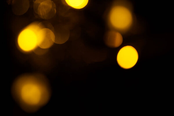 Abstract gold bokeh on black background. Defocused yellow lights, abstract texture.