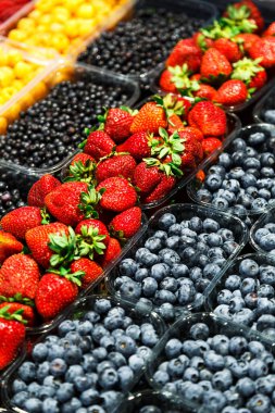 Markette farklı taze meyvelerin renkli karışımı. Ahududu, çilek, yabanmersini ve yabanmersini