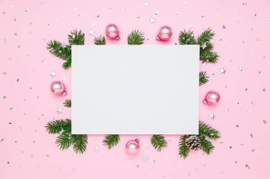 Noel, yeni yıl kartı ve metin için fotokopi alanı. Doğal köknar ağacı dalları çerçevesinde boş beyaz kağıt ve pastel pembe toplar üzerinde gümüş konfeti ile arka planda yatıyordu