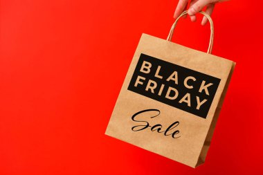 Kara Cuma, kırmızı arka planda izole edilmiş kahverengi el çantası taşıyan kadın. Kara Cuma indirimi, geri dönüşüm, alışveriş ve ekoloji konsepti