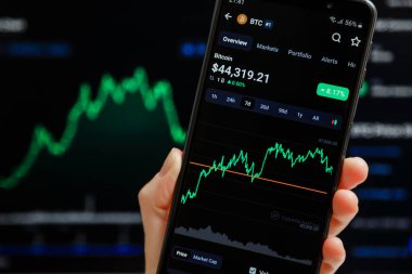 Ukrayna, Odessa - Ekim 9, 2021: CoinMarketCap mobil uygulamasında akıllı telefon ekranında çalışan ticari çift BTC USD, arka planda şamdan şeması ticareti. Güvenilir kripto para birimi veri yetkisi.