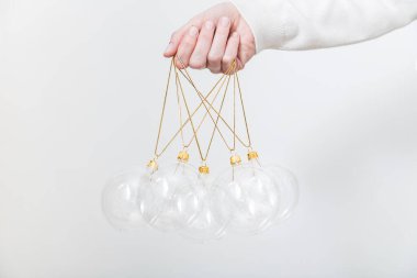 Beyaz arka planda şeffaf cam Noel toplarını tutan kadın. Moda Noel arka planı