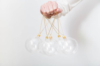 Beyaz arka planda şeffaf cam Noel toplarını tutan kadın. Moda Noel arka planı