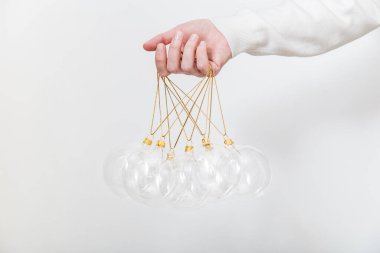 Beyaz arka planda şeffaf cam Noel toplarını tutan kadın. Moda Noel arka planı