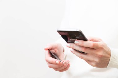 Kyiv, Ukraine - December, 2 2022: Close up of female hands holding credit card and using Samsung smartphone on white background. Woman paying securely online, using banking service. Online shopping.