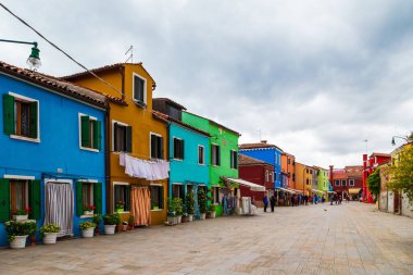 Burano, İtalya - 6 Ekim 2019: Burano Adası, Venedik, İtalya 'daki parlak geleneksel renkli binalar. Turistler muhteşem renkli evleri ve hediyelik eşya dükkanlarıyla eski güzel caddelerde dolaşıyorlar..