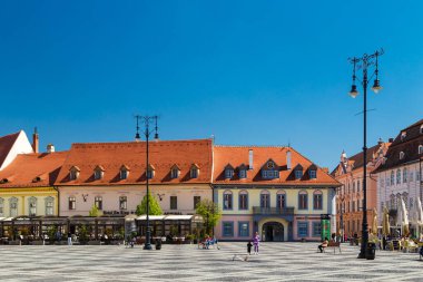 Sibiu, Transilvanya, Romanya - 2 Mayıs 2022: Piata Mare veya Sibiu 'nun tarihi merkezi Büyük Meydan. Turistler açık hava kafeleri, fırınlar ve hediyelik eşya dükkanlarıyla dolaşıyorlar. Parlak güneşli bir gün