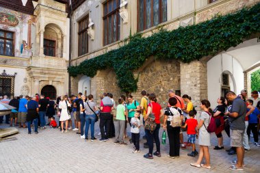 Sinaia, Romania - August 26, 2022: A huge, long line of people waiting for tickets and a guided tour in the courtyard of Peles Castle in Sinaia, Romania. Peak summer season. clipart