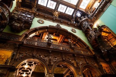 Sinaia, Romanya - 26 Ağustos 2022: Peles kalesindeki Hall of Honor 'da ahşap oymalı sarmal merdiven ve ahşap süsleme. Romanya 'nın Sinaia kentindeki Peles Ulusal Müzesi' nin zengin iç kesimi