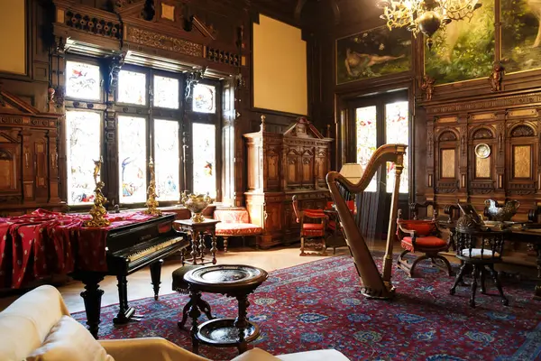 Sinaia, Romanya - 26 Ağustos 2022: The Peles kalesinde piyano ve arp çalan müzik salonu. Romanya 'nın Sinaia kentindeki Peles Ulusal Müzesi' nin zengin iç kesimi.
