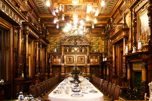 stock image Sinaia, Romania - August 26, 2022: Dining room with served table covered with white tablecloth inside The Peles castle. The rich interior of The Peles National Museum in Sinaia, Romania