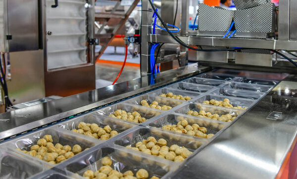 Many meatballs food production line on conveyor belt equipment machinery in factory, industrial food production