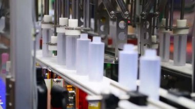 Yüksek kalite otomatik dolgu makinesinde, taşıyıcı bantta beyaz plastik şişeler. Fabrika üretim hattında.