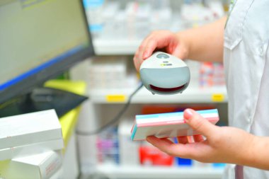 Eczacı eczanede ilaç barkodunu tarıyor.