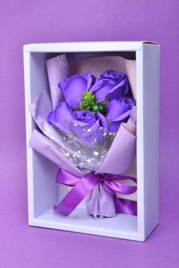 Kırmızı arka planda güller olan mor hediye kutusu. Sevgililer Günü konsepti