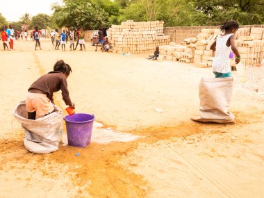 Bour, Senegal, Afrika, Aralık 2021 'de. Kimliği belirsiz Afrikalı çocuklar sokakta çuval yarışı yapıyor. Başlamak için havuzu suyla doldurmaları gerekiyor. Takım sporu çok komik.