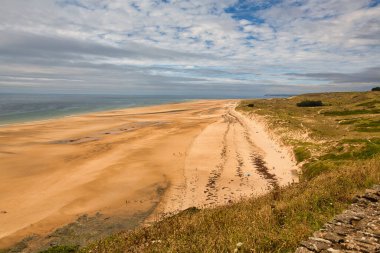 Bulutlu gökyüzü ve doymuş renklerle sahnenin manzarası. Altın saat kum tepeciği, çimen okyanus manzarası. Cotentin Carteret Manche Fransa 'da güzel bir sahil..